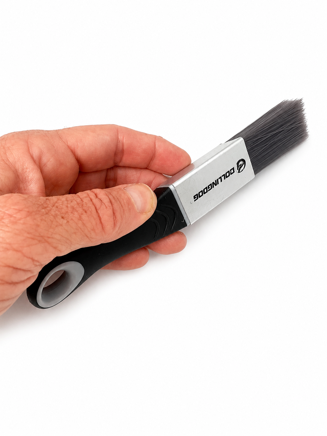 Hand holding a detailing brush with a white background. Small sized detail paint brush